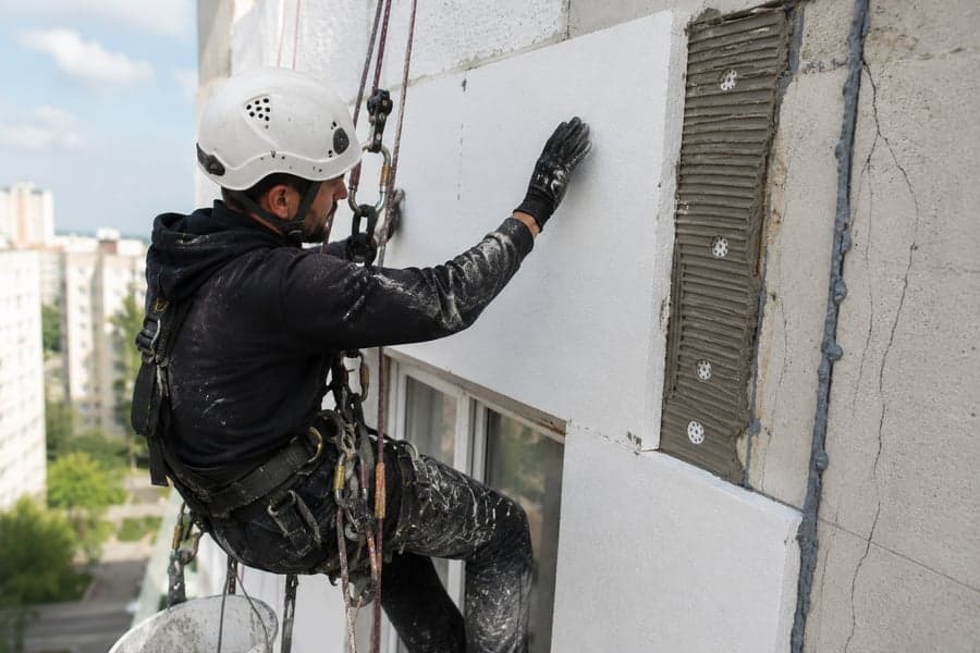Alpinist utilitar montează plăci de polistiren pe fațada unui bloc din Chișinău